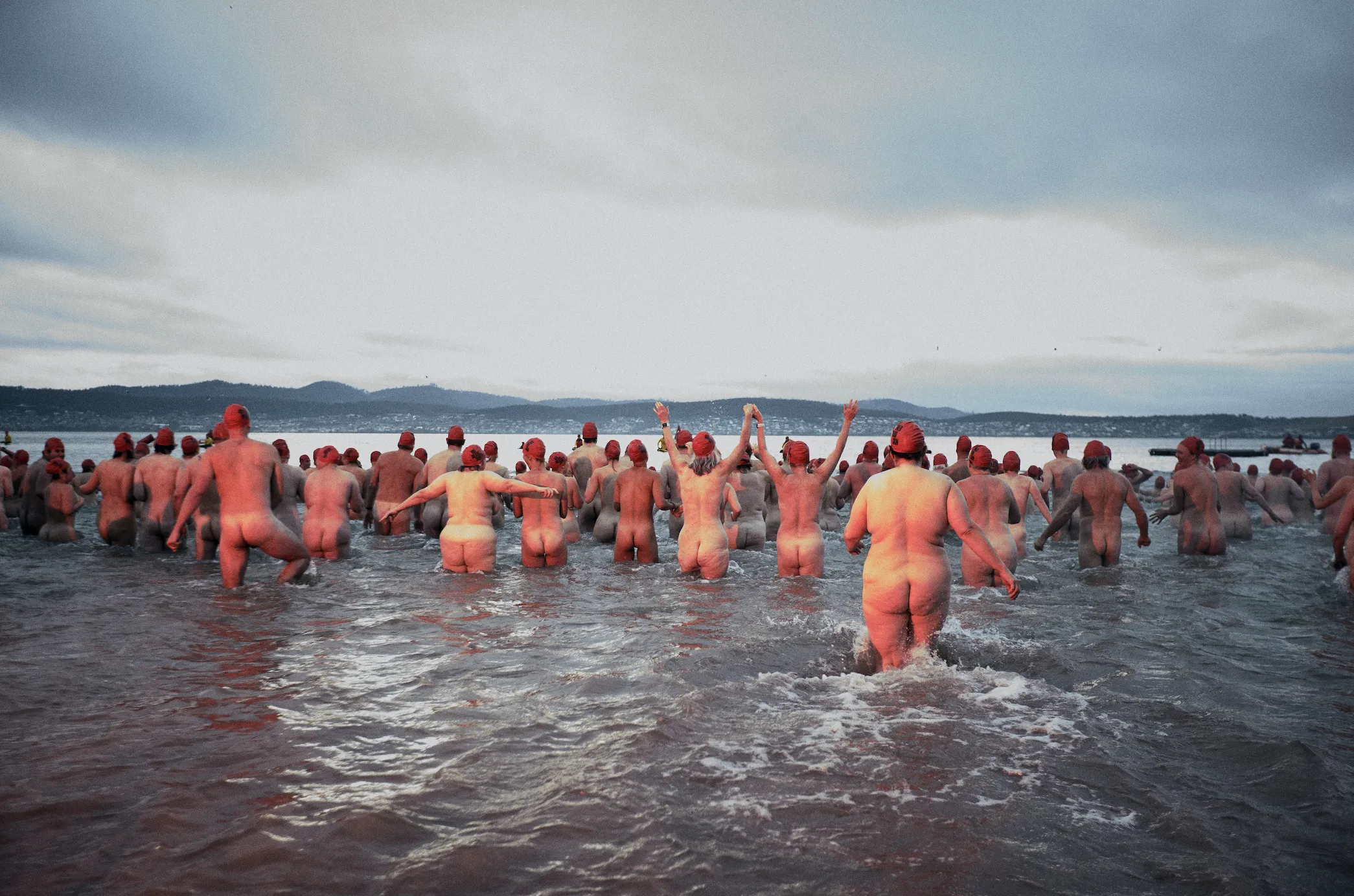 People running into water nude with red caps on