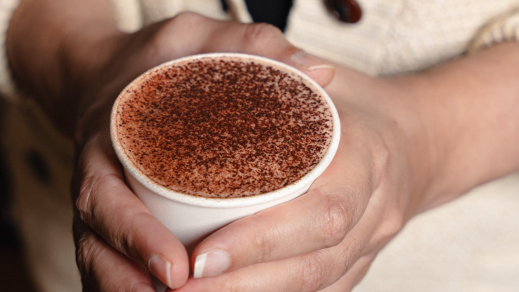 Hands clasped around a cup of hot chocolate.